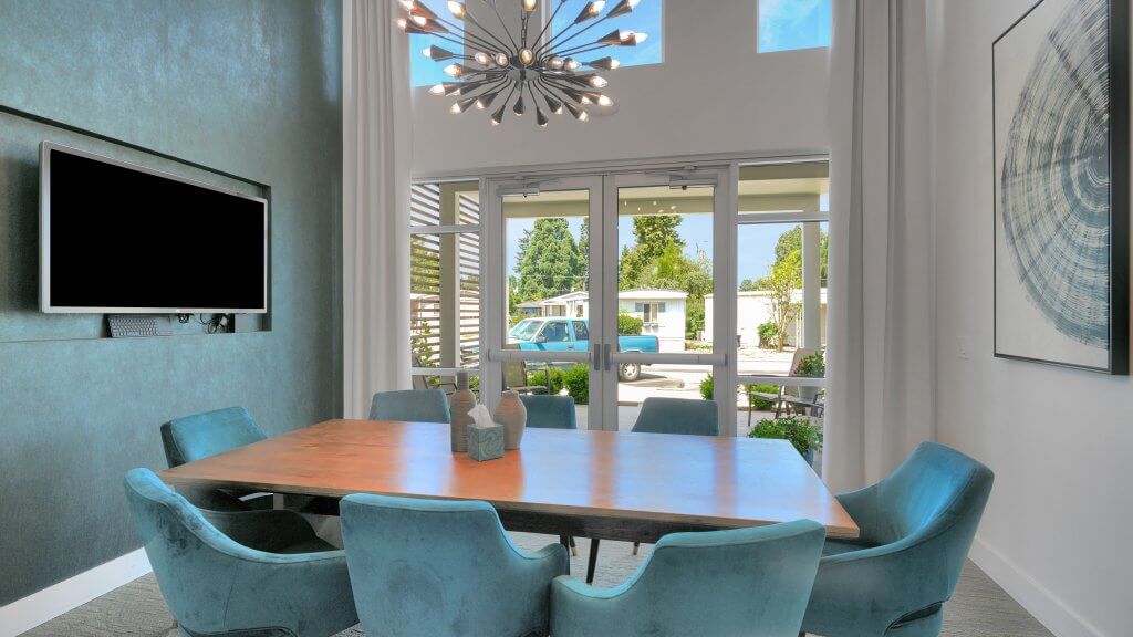 Modern meeting room with a wooden table, teal chairs, large windows, and a wall-mounted TV in salem oregon